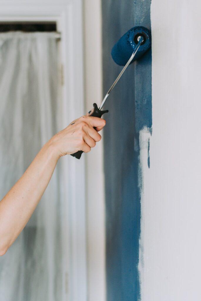 Closeup shot of a person using paint rollers with the color blue